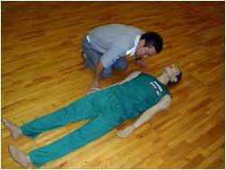 10秒以内で、傷病者の胸や腹部の上がり下がりをみて、普段通りの呼吸をしているかを確認している写真
