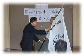 委員長に奉仕団旗が手渡される様子の写真